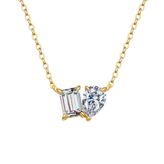 Gold necklace with heart and baguette cut gemstones on a white background